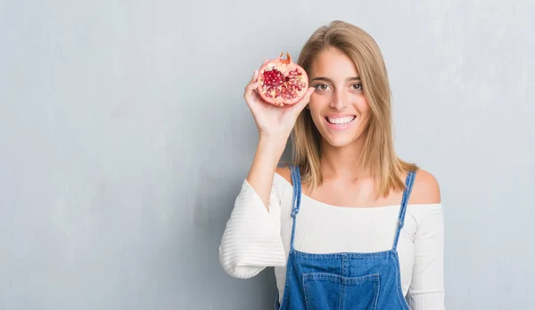 Vacker Ung Kvinna Över Grunge Grå Väggen Hålla Granatäpple Med — Stockfoto