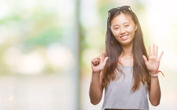 年轻的亚洲妇女戴着太阳镜在孤立的背景显示和指向手指七 而微笑着自信和快乐 — 图库照片