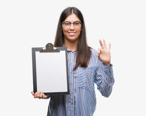 Young Hispanic Woman Holding Clipboard Doing Sign Fingers Excellent Symbol — Stock Photo, Image