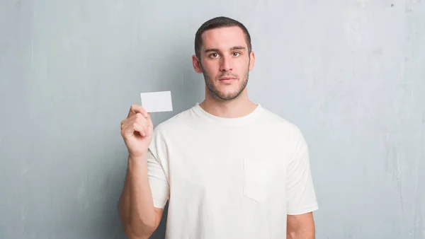 Young Caucasian Man Grey Grunge Wall Showing Blank Visit Card — Stock Photo, Image