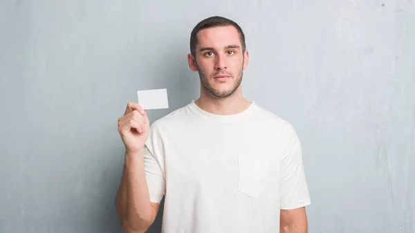 Junger Kaukasischer Mann Über Graue Grunge Wand Zeigt Leere Visitenkarte — Stockfoto