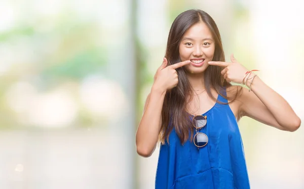 在孤独的背景下 年轻的亚洲妇女微笑着自信地显示和指着手指的牙齿和嘴巴 健康理念 — 图库照片