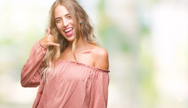 Beautiful young blonde woman over isolated background smiling doing phone gesture with hand and fingers like talking on the telephone. Communicating concepts.