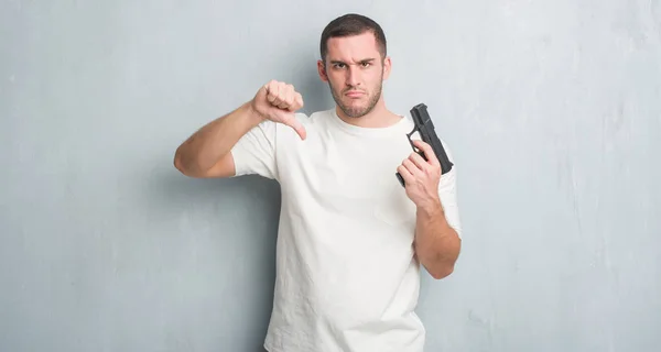 Jovem Homem Criminoso Caucasiano Sobre Parede Grunge Cinza Segurando Arma — Fotografia de Stock