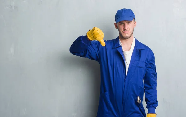 Joven Hombre Caucásico Sobre Pared Gris Grunge Usando Uniforme Mecánico — Foto de Stock