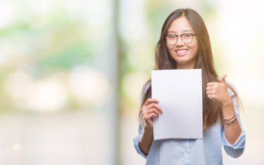 İzole arka plan üzerinde boş kağıt ok işareti, başparmak ile parmak, mükemmel işareti yapıyor kocaman bir gülümseme ile mutlu tutan Genç Asyalı kadın