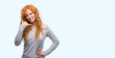 İşin gülümseyen genç Kızıl saçlı kadın telefon hareketi ile el ve parmak telefonda konuşuyor gibi. Kavramları iletişim.