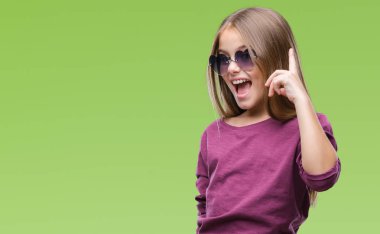 Genç güzel kız başarılı fikirle izole arka plan işaret parmağı üzerinde güneş gözlüğü takıyor. Çıktıktan ve mutlu. Bir numara.