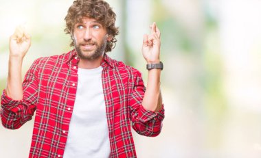 Umut ve gözleri kapalı geçiş parmaklarıyla gülümseyen izole arka plan yakışıklı İspanyol modeli adam. Şans ve batıl kavramı.