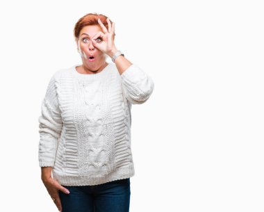 Sürpriz yüz, göz parmaklarının arasından seyir ile ok jest yapıyor izole arka plan üzerinde kış kazak giyen Atrractive üst düzey beyaz Kızıl saçlı kadın şok. İmansız ifade.