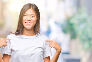 Yüzünde gülümseme ile kendinden emin görünüyorsun, kendini gururlu ve mutlu parmakları ile işaret izole arka plan üzerinde Genç Asyalı kadın.