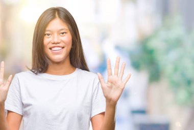 Genç Asyalı kadın gösterilen ve parmakları ile işaret izole arka plan üzerinde kendinden emin ve mutlu gülümseyerek süre sekiz numara.