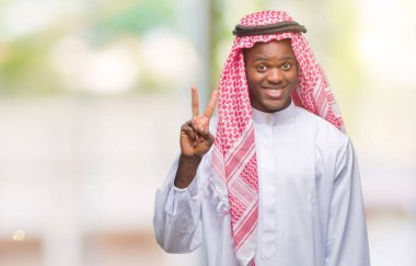 Geleneksel keffiyeh gösterilen ve parmakları ile işaret izole arka plan üzerinde giyen genç Arapça Afrika adam ikincisi ise kendinden emin ve mutlu gülümseyerek.