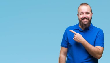 İzole arka neşeli bir gülümseme ile el ve parmak kadar kameraya bakarak yüzündeki mutlu ve doğal ifade ile yan ile işaret yüz üzerinde mavi gömlek giymiş genç beyaz hipster adam.