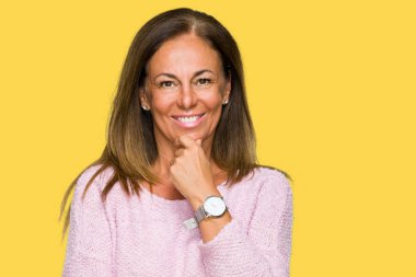 Emin çapraz kollar ve çeneme kaldırdı el ile gülümseme ile kameraya bakarak izole arka plan üzerinde kış kazak giyen güzel orta yaş yetişkin kadın. Pozitif düşünce.