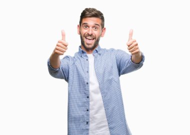 El ile pozitif jest yapıyor onaylama izole arka plan üzerinde beyaz t-shirt giyen genç yakışıklı adam başparmak gülümseyen ve başarı için mutlu. Kamera, kazanan jest arıyorsunuz.