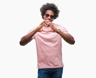 Afro Amerikalı adam aşık kalp simgesi ve elleriyle şekil gösteren gülümseyen izole arka plan üzerinde güneş gözlüğü takıyor. Romantik kavramı.