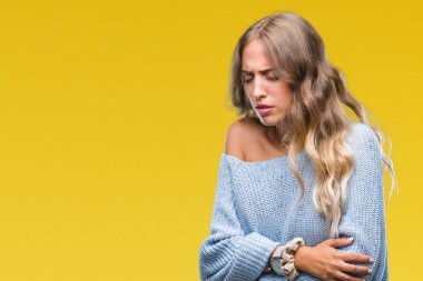 Üzerinde kış kazak giyen güzel genç sarışın kadın izole mide üzerinde el ile arka plan çünkü mide bulantısı, ağrılı hastalık hasta hissediyor. Ağrısı kavramı.