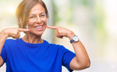 Orta yaş üst düzey İspanyol kadın kendinden emin gösterilen ve işaret parmakları diş ve ağız ile gülümseyen izole arka plan yüzünden. Sağlık kavramı.