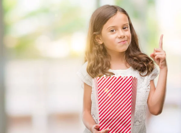 幸せそうな顔 ナンバーワンのアイデアや質問ポインティング指で驚いてポップコーンを食べてヒスパニックのブルネットの少女 — ストック写真