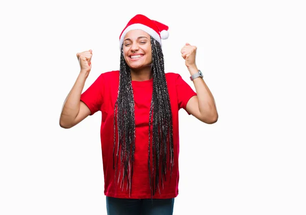 年轻的编织头发非洲裔美国女孩戴着圣诞节帽在孤立的背景庆祝惊讶和惊讶的成功与手臂抬起和睁大眼睛 优胜者概念 — 图库照片