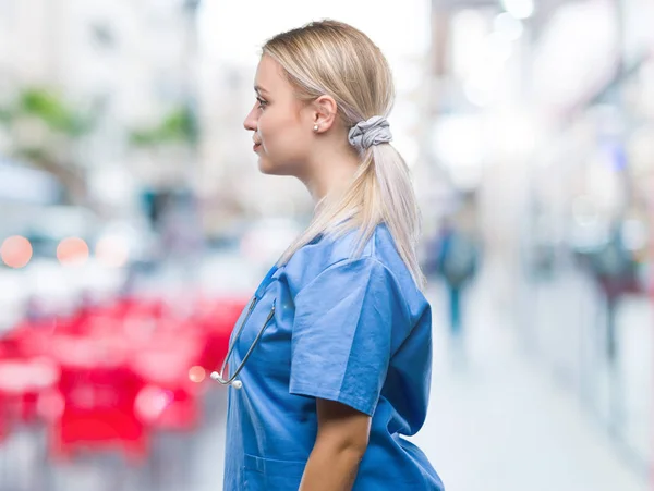 Young blonde surgeon doctor woman over isolated background looking to side, relax profile pose with natural face with confident smile.