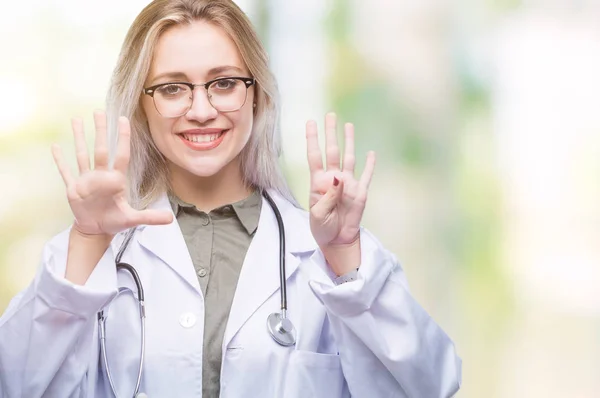 年轻的金发医生妇女在孤立的背景显示和指向与手指数字九同时微笑自信和快乐 — 图库照片
