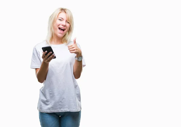 年轻美丽的金发女子使用智能手机在孤立的背景快乐与大微笑做 拇指与手指 优秀的标志 — 图库照片