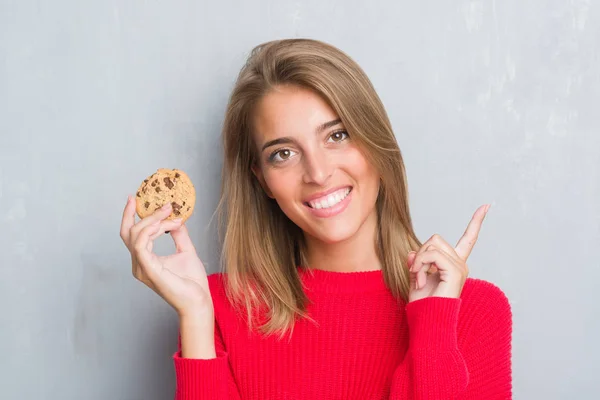Piękna Młoda Kobieta Streszczenie Szary Mur Jedzenie Czekolady Chip Cooky — Zdjęcie stockowe