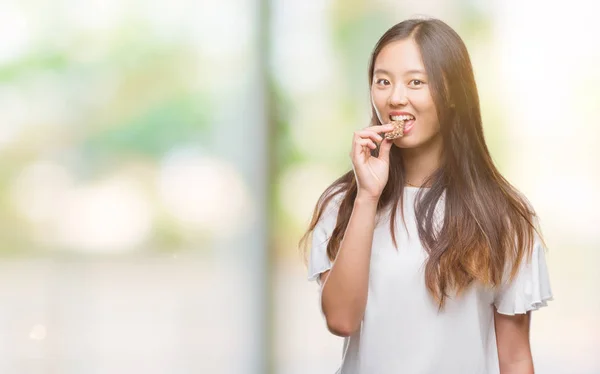 スマートの顔は深刻な思考に自信を持って式に分離された背景に食べるチョコレート エネルギッシュな若いアジア女性 — ストック写真
