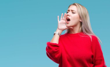 Bağırarak ve ağzı üzerinde el ile yan için çığlık izole arka plan üzerinde kış kazak giyen genç sarışın kadın. İletişim kavramı.