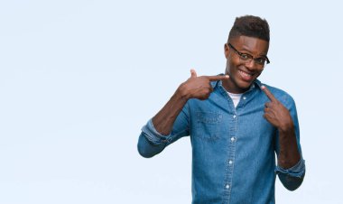 Afrikalı-Amerikalı genç kendinden emin gösterilen ve işaret parmakları diş ve ağız ile gülümseyen izole arka plan üzerinde. Sağlık kavramı.
