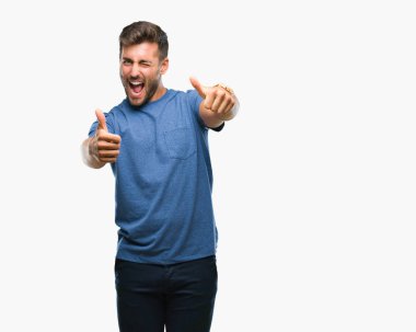 Yakışıklı delikanlı el ile pozitif jest yapıyor onaylama izole arka plan üzerinde başparmak gülümseyen ve başarı için mutlu. Kamera, kazanan jest arıyorsunuz.