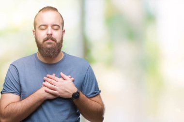 Göğüs kapalı gözler ve yüzünde minnettar jest ile izole arka plan ile gülümseyen üzerinde genç beyaz hipster adam eller. Sağlık kavramı.