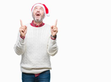 Noel şapka izole arka plan üzerinde orta yaş ağarmış komuta sizde hayrete ve yukarıya bakıyor ve parmakları ile işaret ve silah kaldırdı şaşırttı.