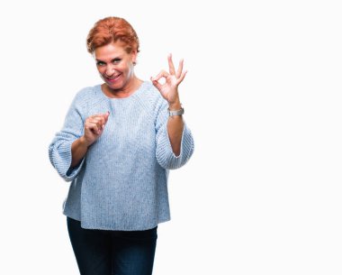 İzole arka plan el ve parmaklar ok işaretiyle yapıyor olumlu gülümseyen üzerinde kış kazak giyen Atrractive üst düzey beyaz Kızıl saçlı kadın. Başarılı ifade.