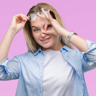 Gülümseyen, parmakları ile mutlu yüz üzerinden seyir göz el ile ok jest yapıyor izole arka plan üzerinde gözlük takan Genç beyaz iş kadını.