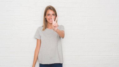 Güzel ve genç birbayan gösterilen ve parmakları ile işaret beyaz tuğla duvarın üzerinden ikincisi ise kendinden emin ve mutlu gülümseyerek.