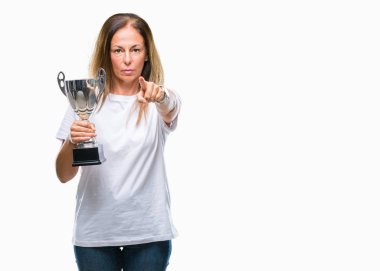 Orta yaş İspanyol kazanan kadın kutluyor Ödülü holding kupa izole arka kamera ve size parmak ile işaret üzerine, el işareti, pozitif ve kendinden emin bir jest ön