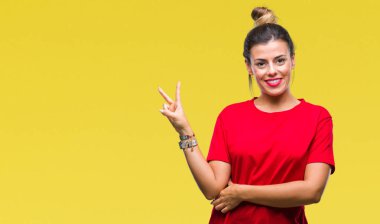 Genç güzel kadın mutlu yüz zafer işareti yaparken kameraya göz kırpıyor ile gülümseyen izole arka plan yüzünden. İki numaralı.