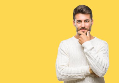 Emin çapraz kollar ve çeneme kaldırdı el ile gülümseme ile kameraya bakarak izole arka plan üzerinde kış kazak giyen genç yakışıklı adam. Pozitif düşünce.