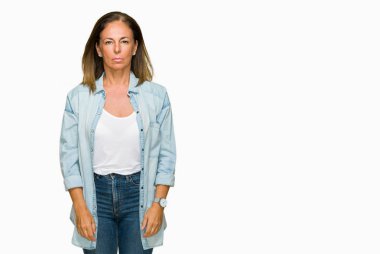 Orta yaş yetişkin kadın yüzünde ciddi bir ifade ile izole arka plan üzerinde rahat kot gömlek giymiş. Basit ve doğal kameraya bakıyor.