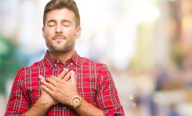 Yakışıklı delikanlı ile gülümseyen izole arka plan üzerinde kapalı gözler ve yüzünde minnettar jest ile göğüs üzerinde eller. Sağlık kavramı.