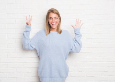 Güzel ve genç birbayan gösterilen ve parmakları ile işaret beyaz tuğla duvarın üzerinden sekiz kendinden emin ve mutlu gülümseyerek iken numara.