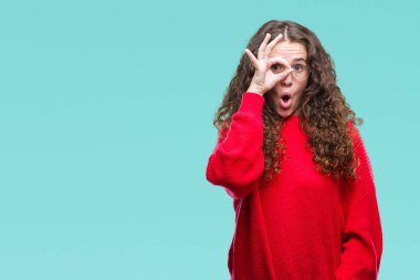 Sürpriz yüz, göz parmaklarının arasından seyir ile ok jest yapıyor izole arka plan üzerinde gözlük ve kış kazak giyen güzel esmer kıvırcık saçlı Genç kız şok. İmansız ifade.