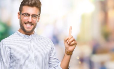 Kameraya bakarak yan el ve parmak ile işaret eden genç yakışıklı adam yüzünde kocaman bir gülümseme ile izole arka plan üzerinde.