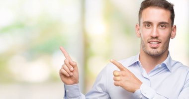 Gülümseyen ve iki ile işaret kamera bakarak yakışıklı genç işadamı eller ve yan parmak.