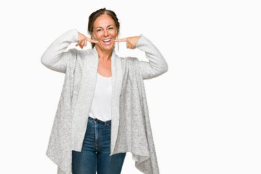 Kendinden emin gösterilen ve işaret parmakları diş ve ağız ile gülümseyen izole arka plan üzerinde kış kazak giyen güzel orta yaş yetişkin kadın. Sağlık kavramı.