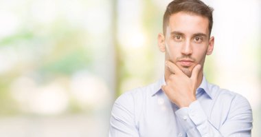 Yakışıklı genç işadamı emin çapraz kollar ve çeneme kaldırdı el ile gülümseme ile kameraya bakıyor. Pozitif düşünce.