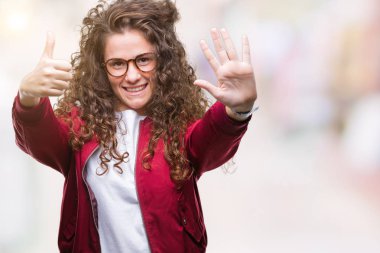 Ceket ve gözlük gösterilen ve parmakları ile işaret izole arka plan üzerinde giyen güzel esmer kıvırcık saçlı Genç kız kendinden emin ve mutlu gülümseyerek süre 6 numara.